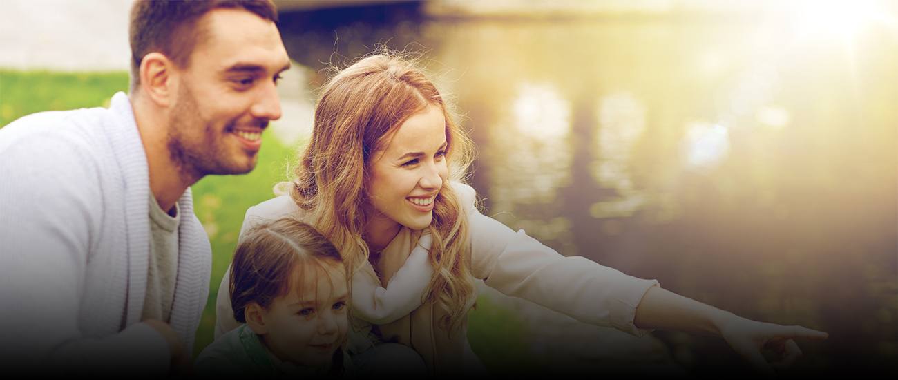 Smiling family of three sitting outdoors
